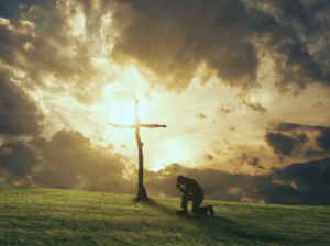 Man at cross sunset